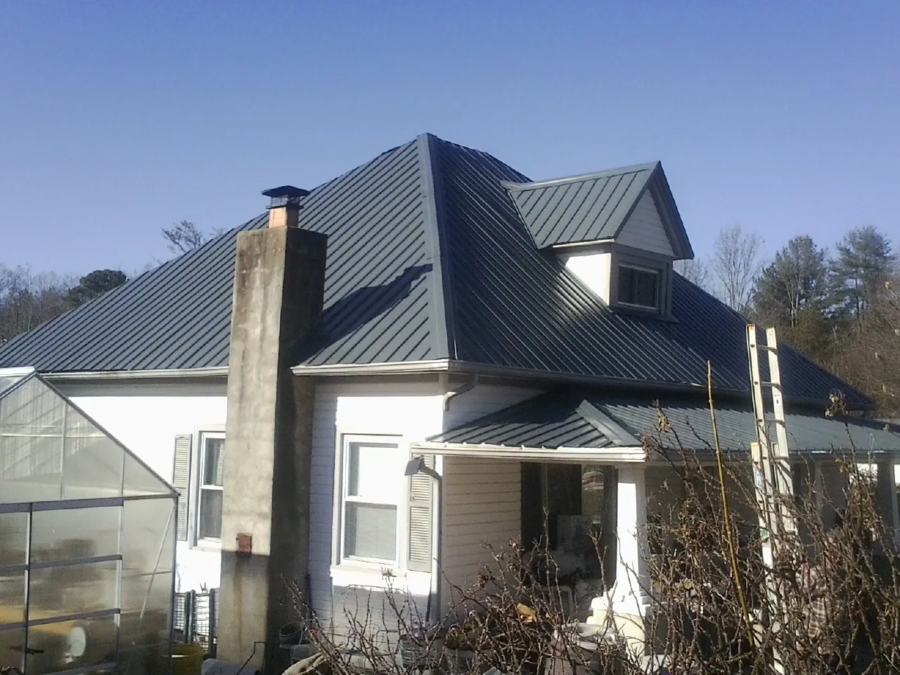 Dark blue standing seam metal roof on a white farmhouse with dormer — Slate & Tile Roof Repair by Roofing Brothers in East Providence