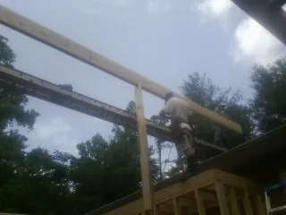 Carpenter setting a ridge beam over a new addition frame — Ice Dam Removal by Roofing Brothers in East Providence