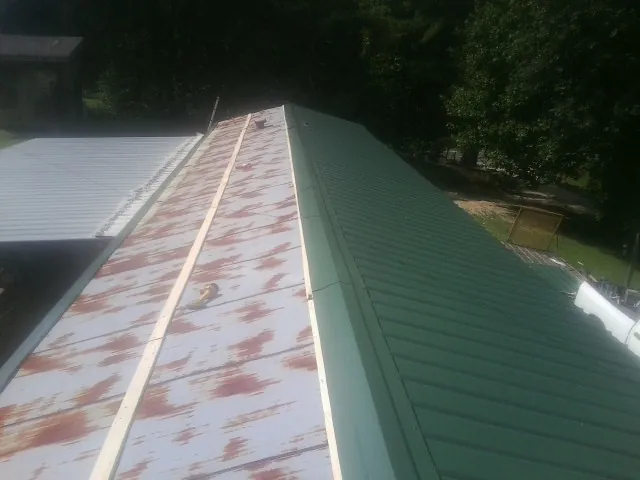 Old rusted panels beside newly installed green metal roofing — Wind Damage Roof Repair by Roofing Brothers in East Providence