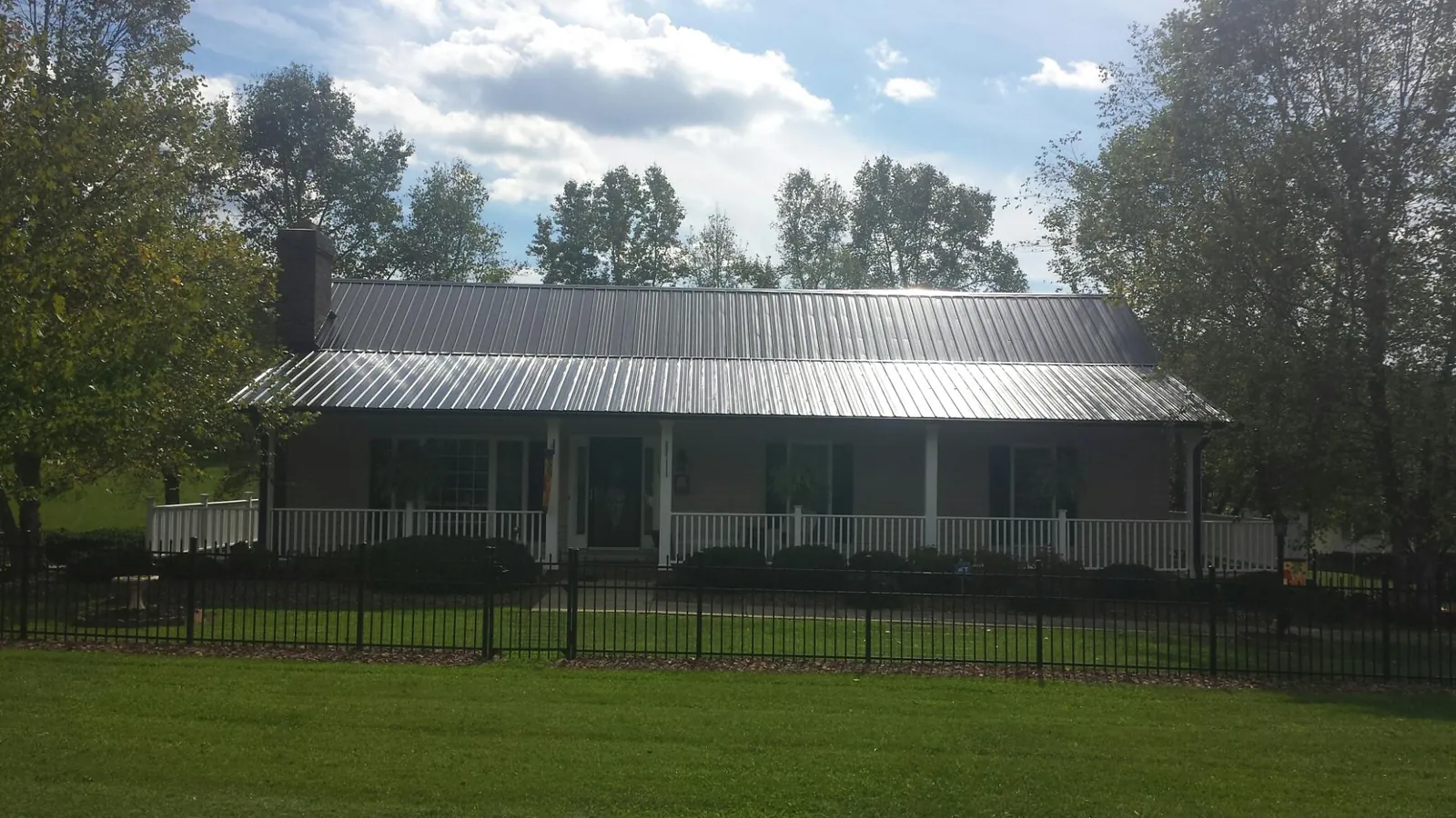 Gray metal roof on a brick ranch with a full width front porch — Gutter Guard Installation work by our crew in East Providence