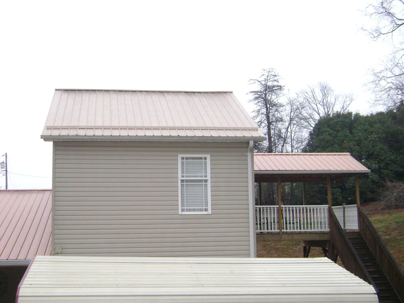 Tan metal roofs on a two story addition and attached porch, from a Roof Replacement job in East Providence