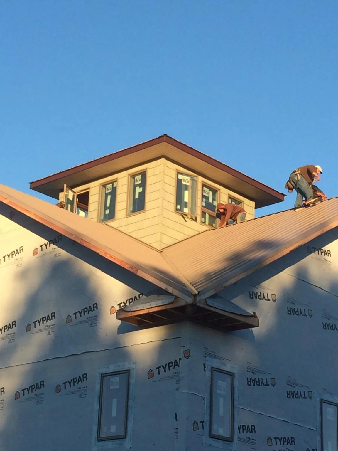 Roofers working around a rooftop cupola on a new metal roof at sunset — Roof Waterproofing in East Providence by Roofing Brothers